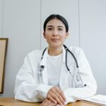 A female doctor confidently sits at her desk, ready for consultation in a medical office.